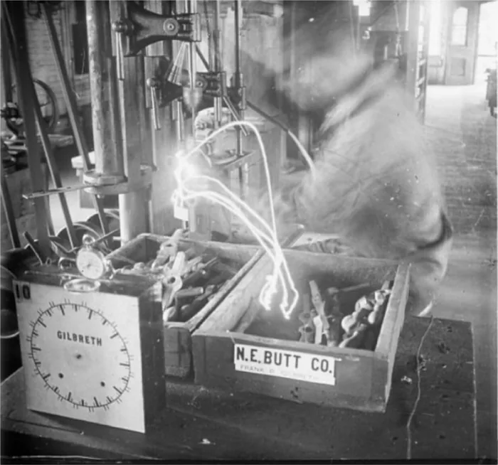 A Gilbreth chronocyclegraph photograph: ribbons of light tracing a worker's hand motions beside the Gilbreth timing clock.