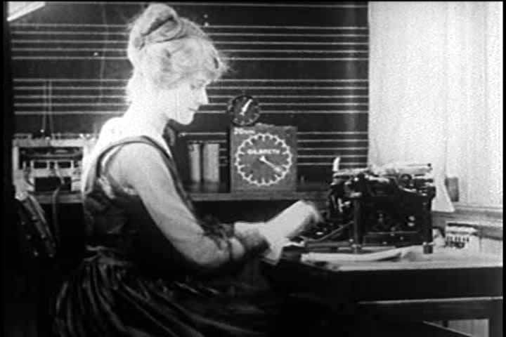 Gilbreth micromotion film still: a typist at her machine with the Gilbreth microchronometer clock in frame.